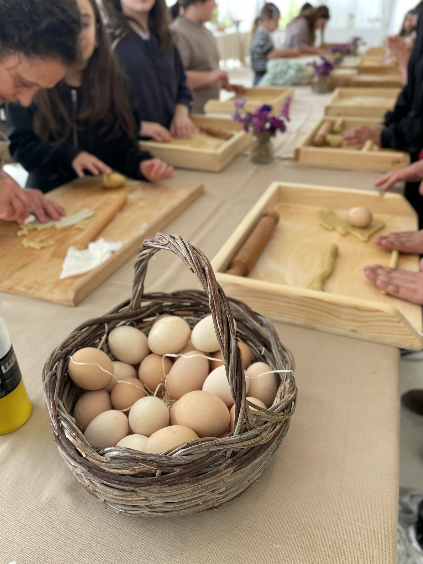 Uova nel cestino e mani che impastano sulle tavole di legno
