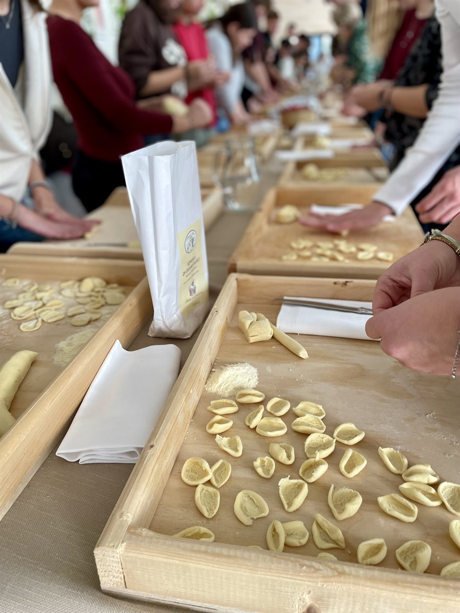 Un gruppo al laboratorio di pasta fresca: mani e orecchiette sulle tavole di legno