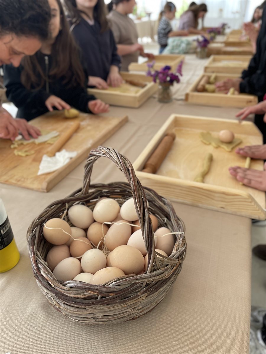 Il laboratorio di pasta fresca: un cestino di uova e le tavole di legno con la pasta in lavorazione