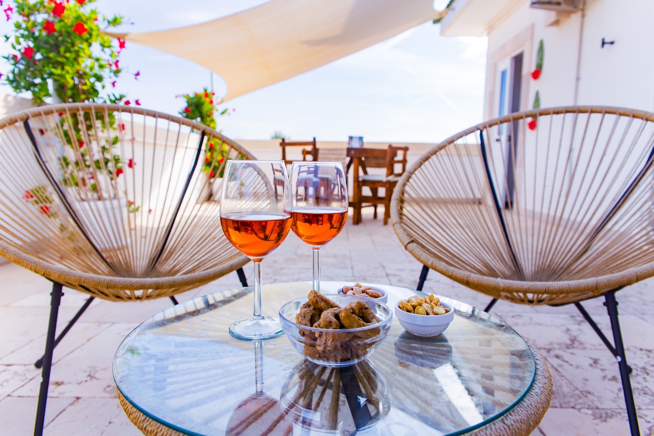 Due calici e ciotole di stuzzichini su un tavolino in terrazza.