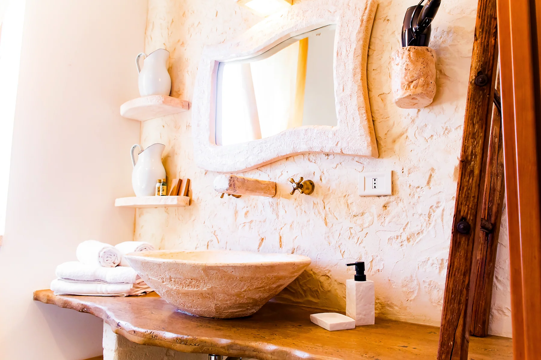 Lavabo in pietra e specchio nel bagno di una camera della Masseria